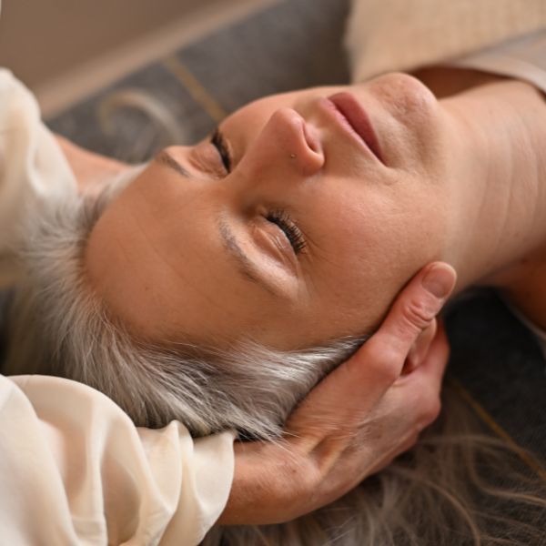 Eine Klientin ruht entspannt während einer sanften, nährenden Behandlung am Kopf im Therapeutenzentrum für alternative Frauenheilkunde Hamburg.